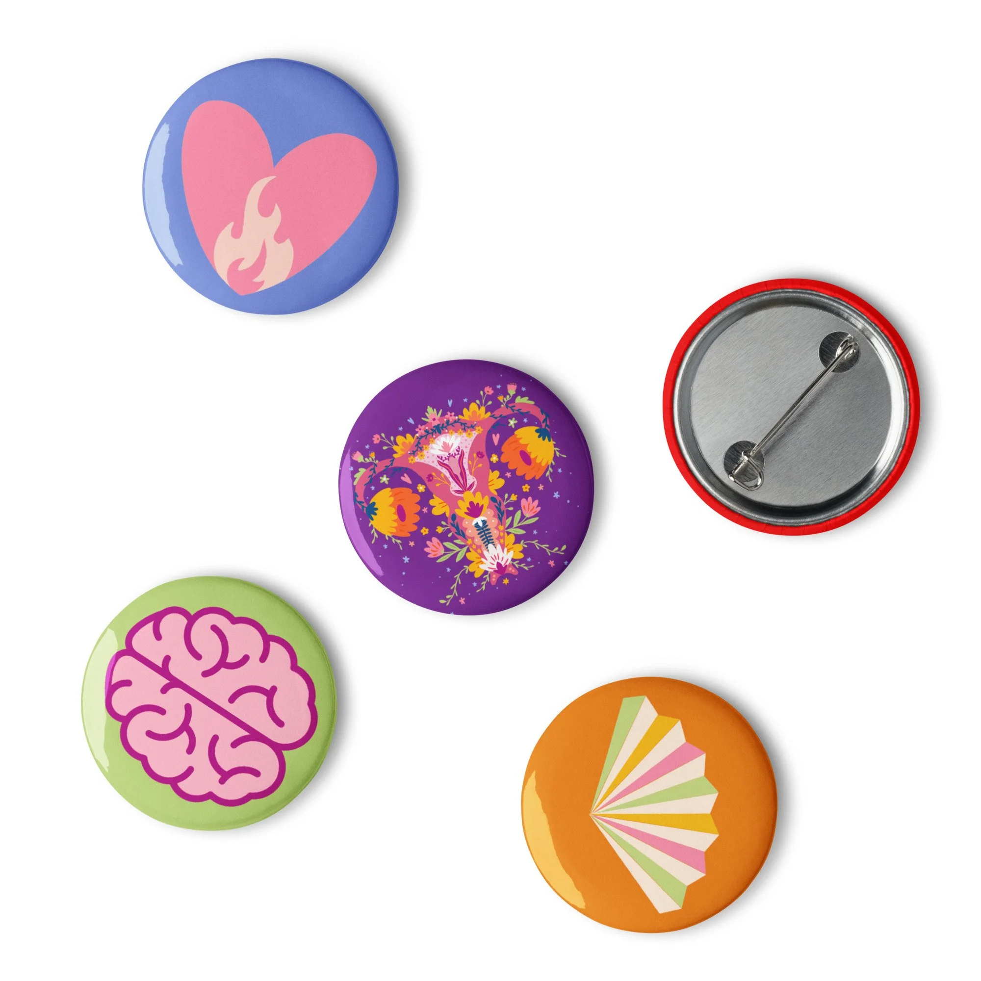 Collection of decorative badges with various designs, including a pink heart with flame, colorful floral pattern, pink brain silhouette, and rainbow-striped fan, arranged on a white background. Up Yours Menopause!' merchandise.