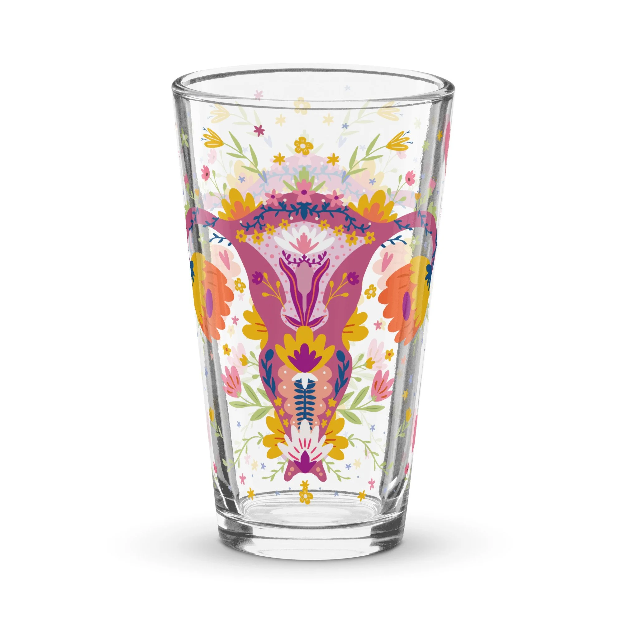 A clear glass with colorful, intricate floral and symmetrical patterns in pink, yellow, green, and purple, resembling a design inspired by traditional or folk art. Up Yours Menopause!' merchandise.