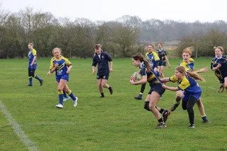 Children playing rugby on a grassy field during daytime.