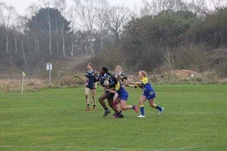 Kids playing rugby on a grassy field.
