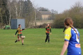Children playing soccer in a grassy field.