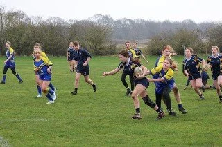 Girls playing rugby on a grassy field