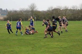 Children playing rugby match on grassy field