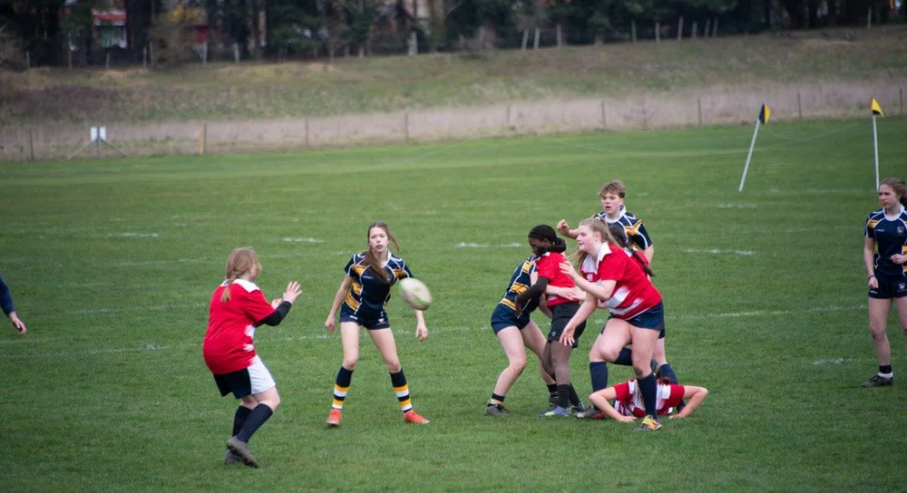 Children playing rugby on a green field during daytime.