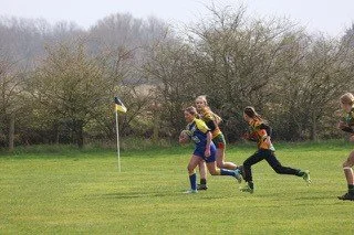 Children playing flag football on a grassy field.