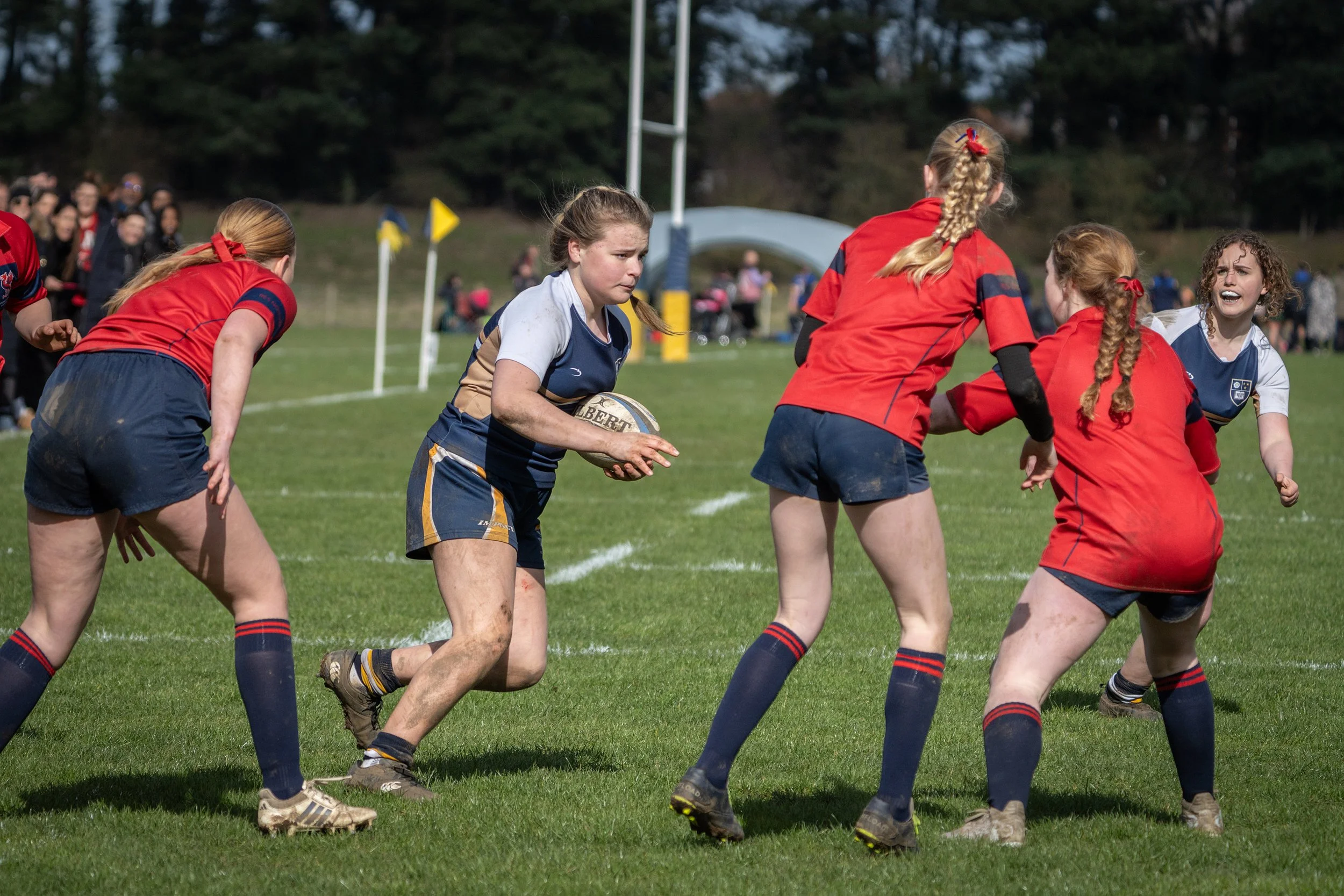 Girls playing rugby on a grassy field during the daytime.