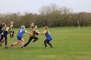 Children playing rugby on a grassy field during daytime.
