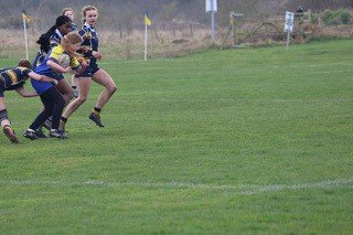 Children playing rugby on a grassy field