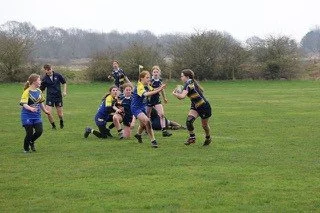Women playing rugby on a grassy field