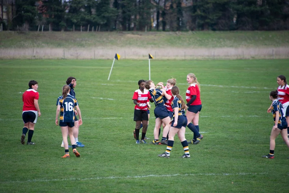 Rugby players from opposing teams engaging in a physical contest during a match on a grassy field.