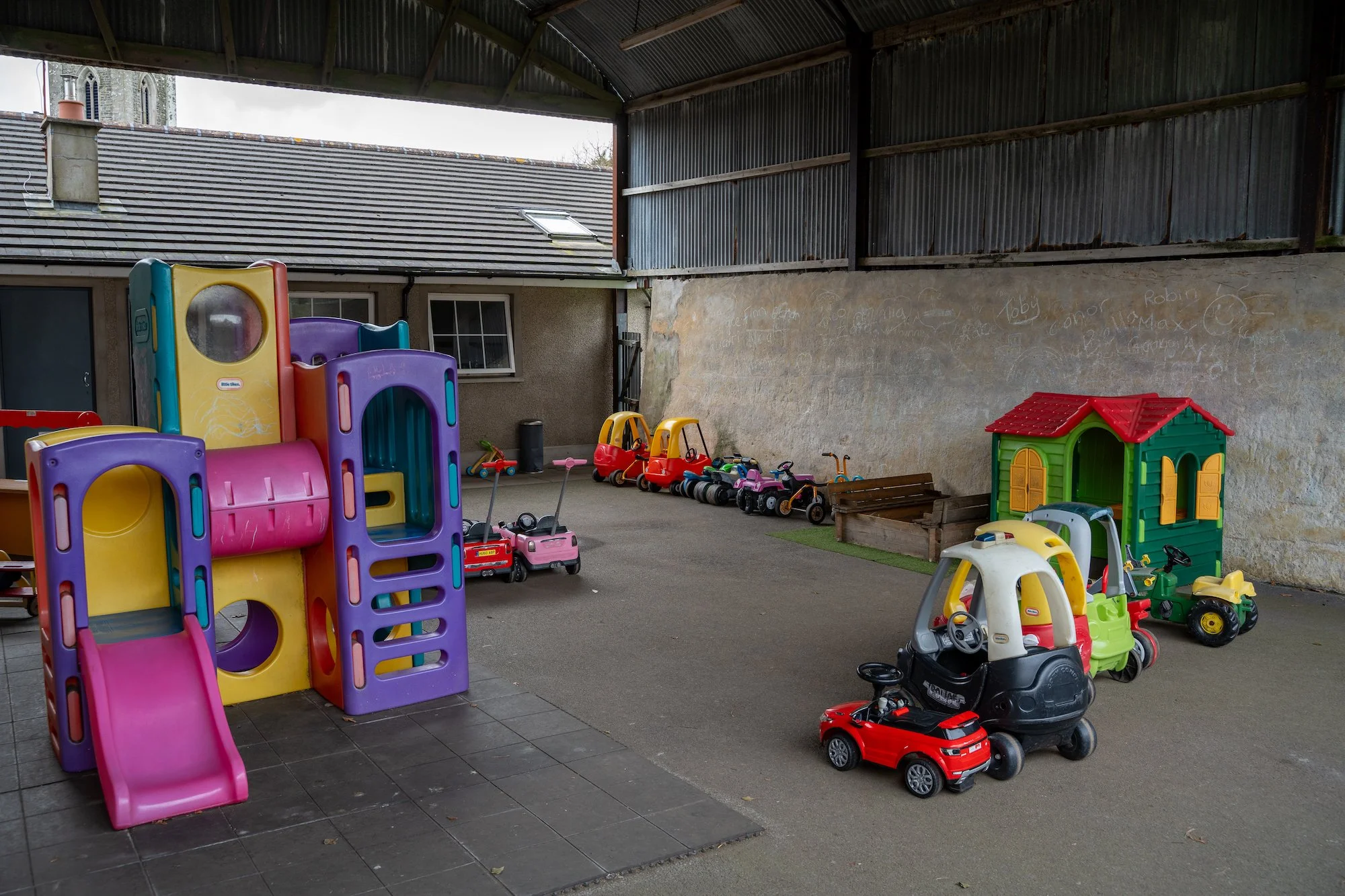 Indoor children’s play area with various colorful toy cars, small slides, and a playhouse.