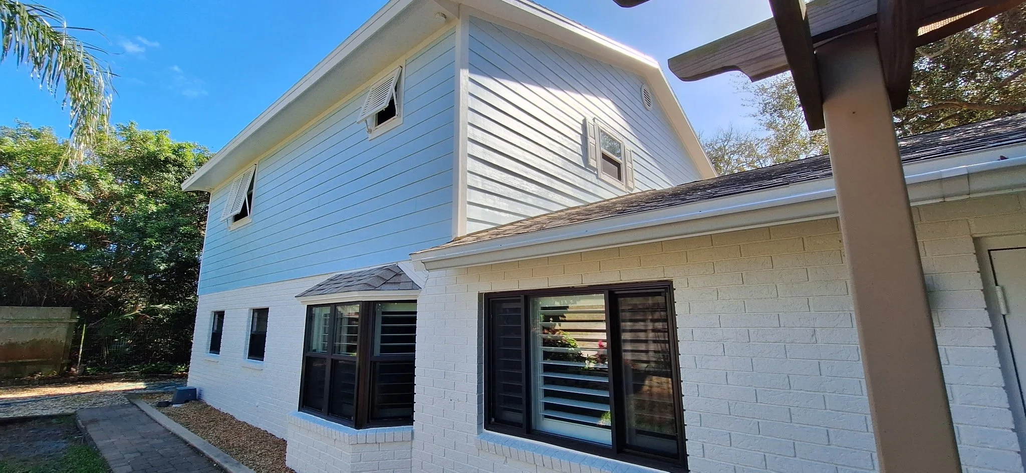 Soft coastal siding paired with white brick creates a timeless exterior design for this New Smyrna Beach home.