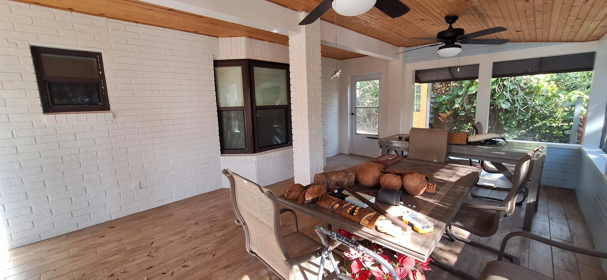 Interior view of a screened porch with freshly painted white brick, natural wood ceiling, and coastal finishes in New Smyrna Beach.