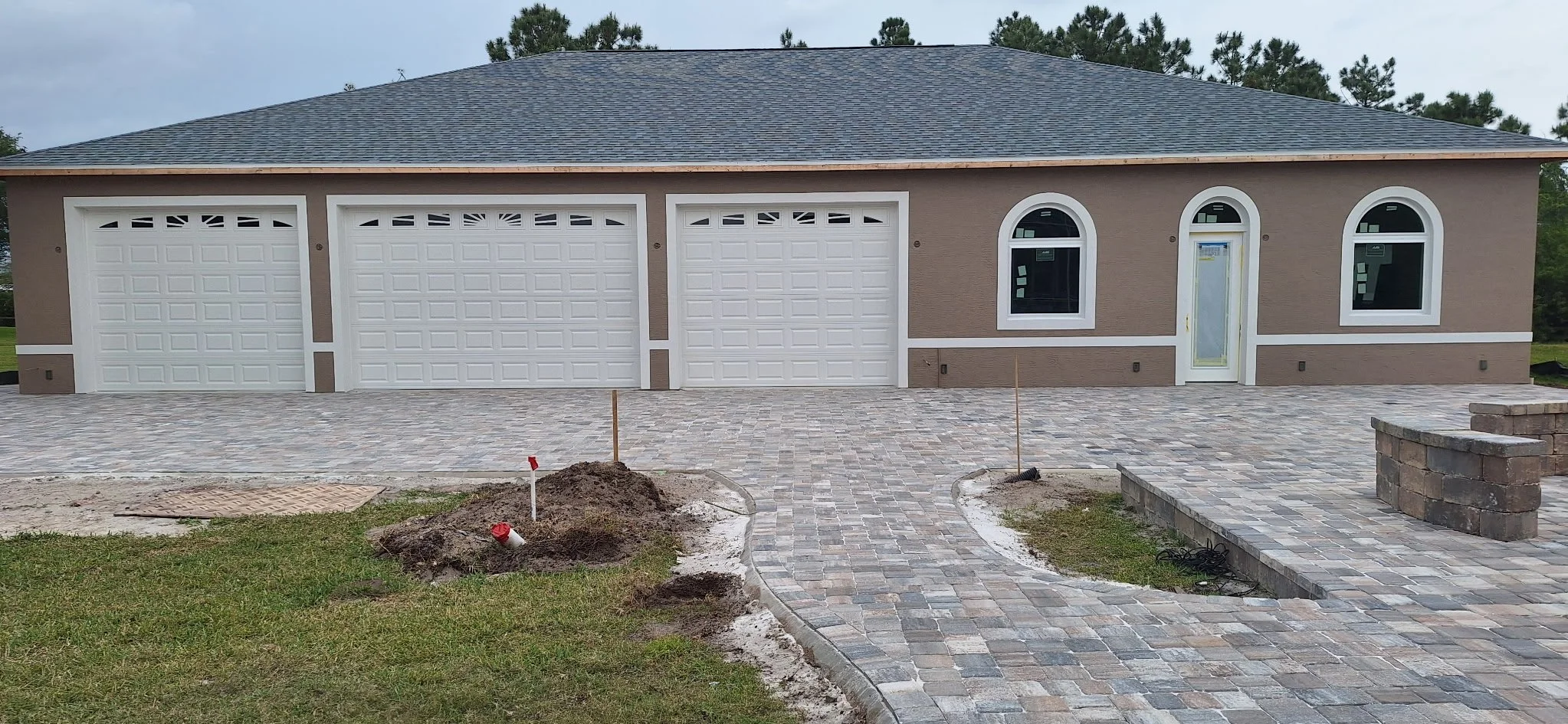 Newly constructed house with a three-car garage, a paved driveway, and a front yard with some landscaping work in progress.