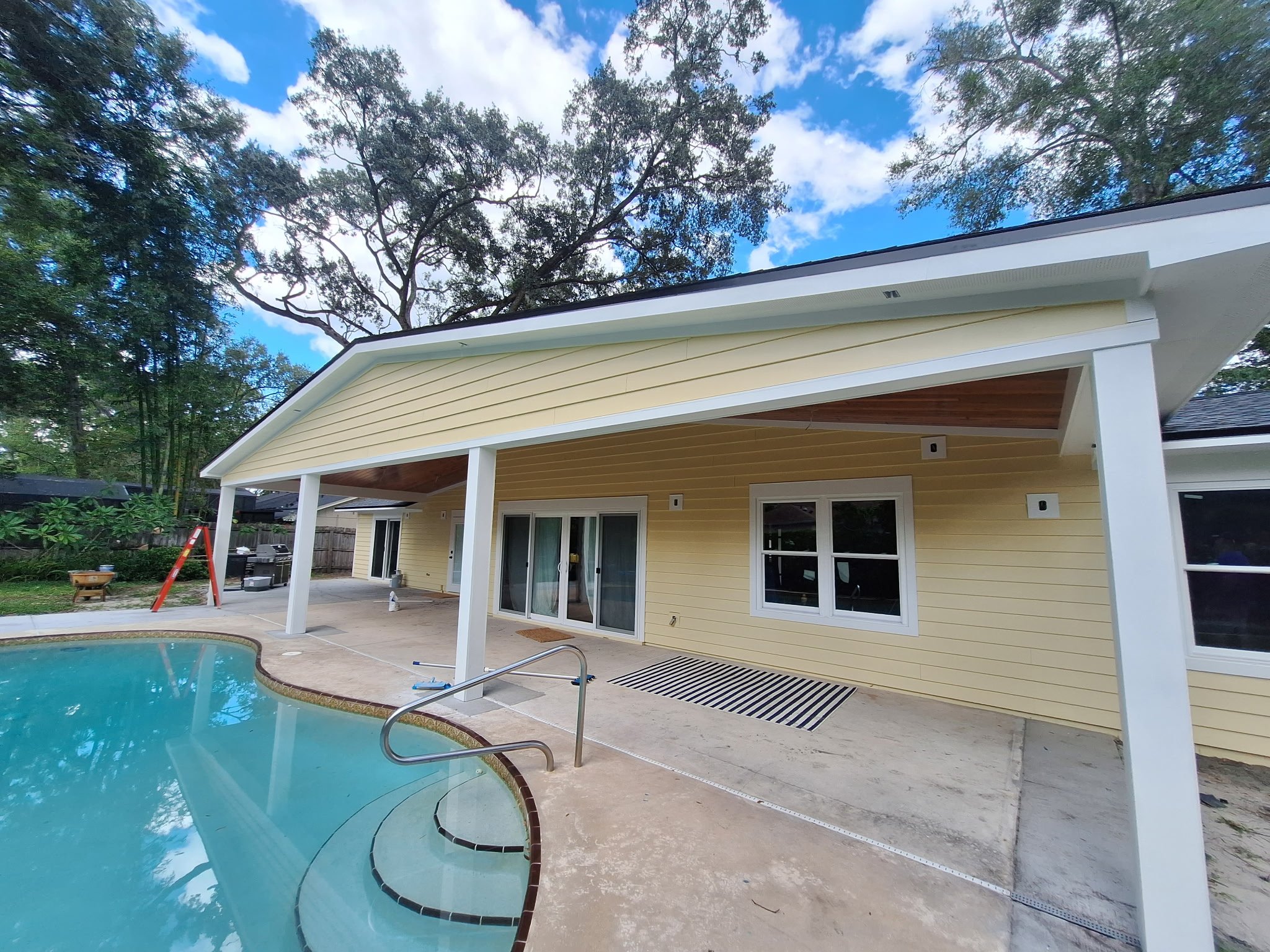 Backyard pool area with freshly painted yellow siding in Longwood Florida