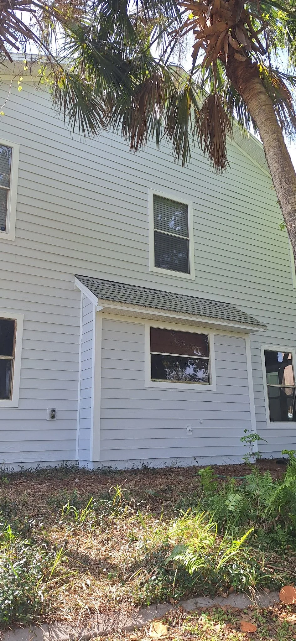 White siding exterior painting in Melbourne Florida with palm tree backdrop.