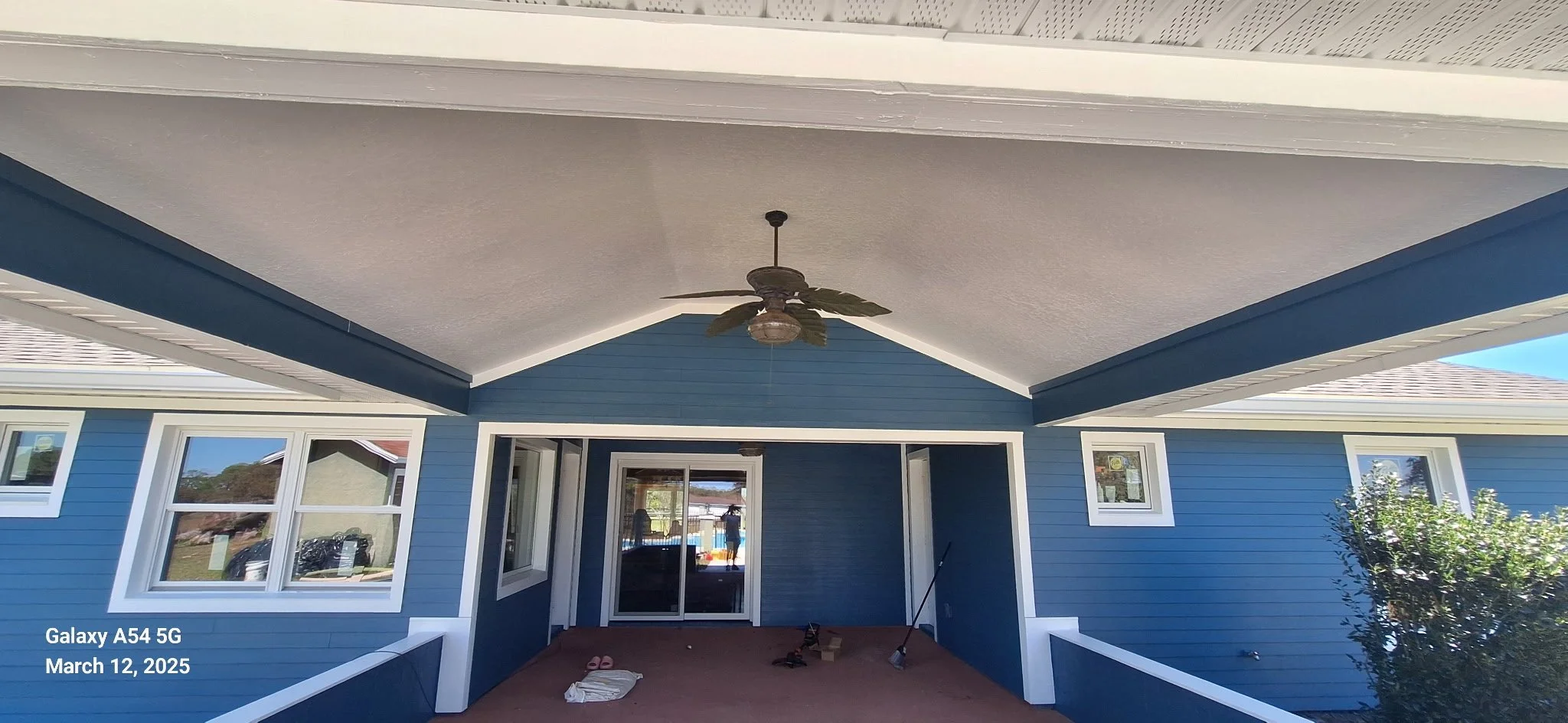 Covered backyard patio of Ocala Florida home with modern blue exterior paint and white trim