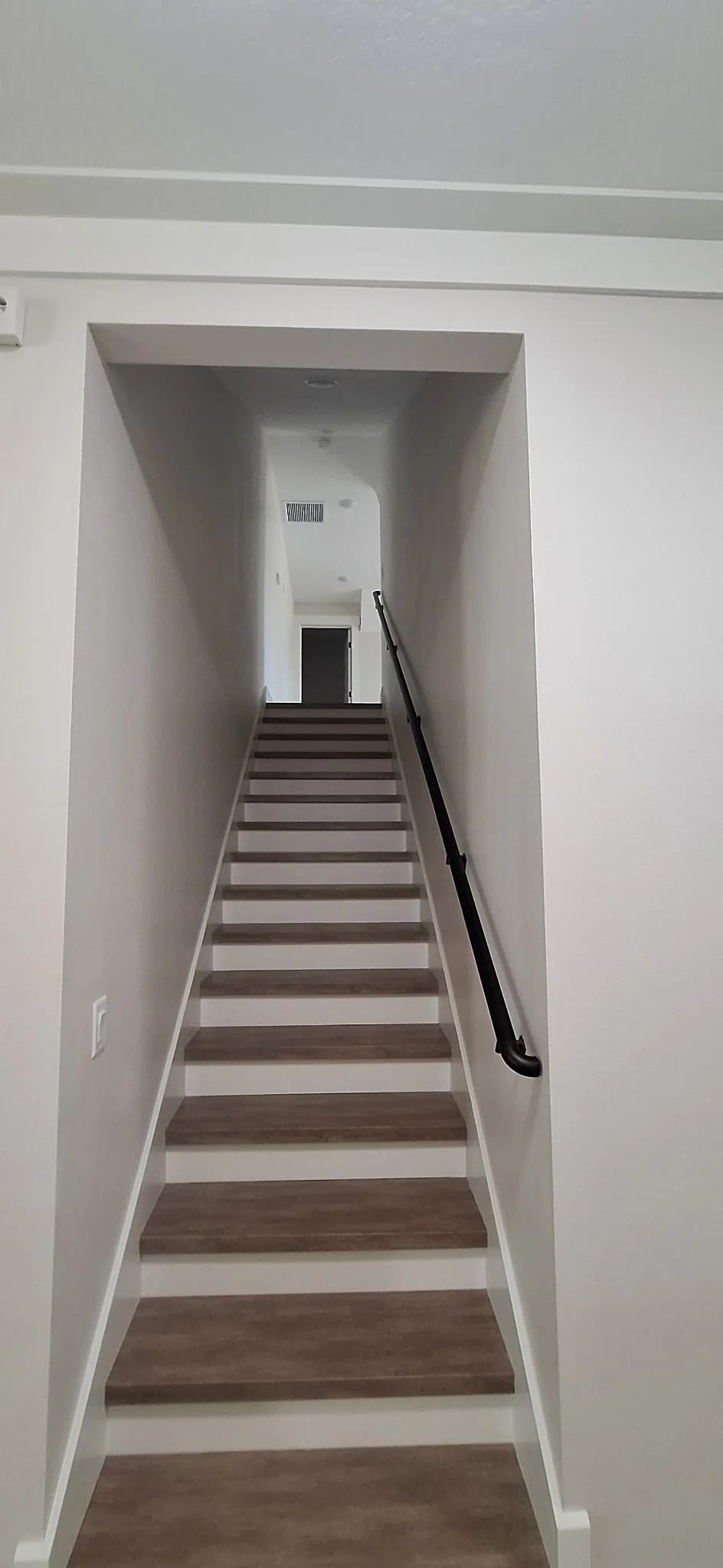 Freshly painted staircase with neutral walls and wood steps inside a new construction home in Sanford, FL.