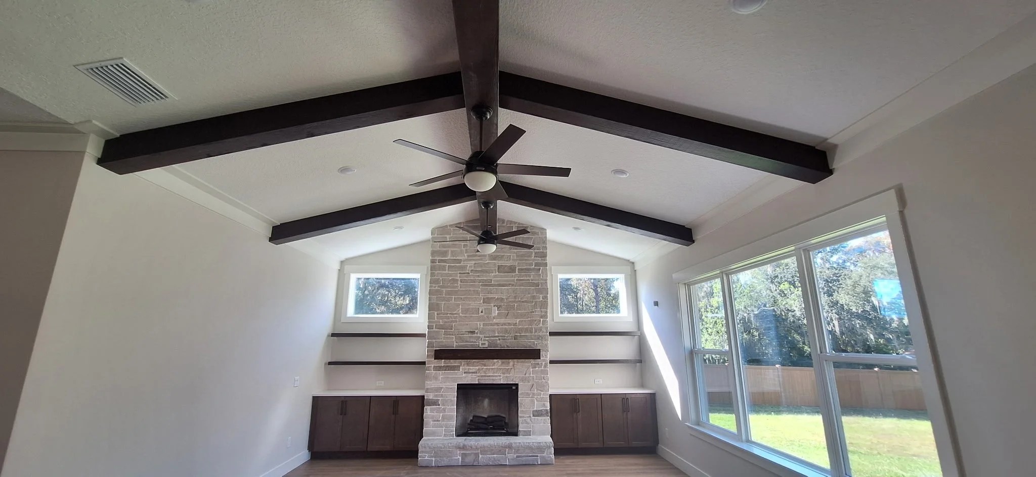 Stunning living room interior paint finish with exposed beams and a stone fireplace feature.