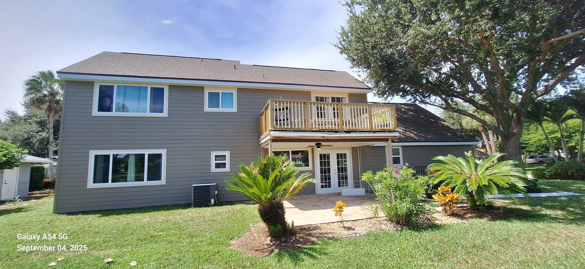 After exterior house painting in Melbourne FL showing taupe and neutral Hardie Board siding with white trim, completed by Coats of Quality Painting.