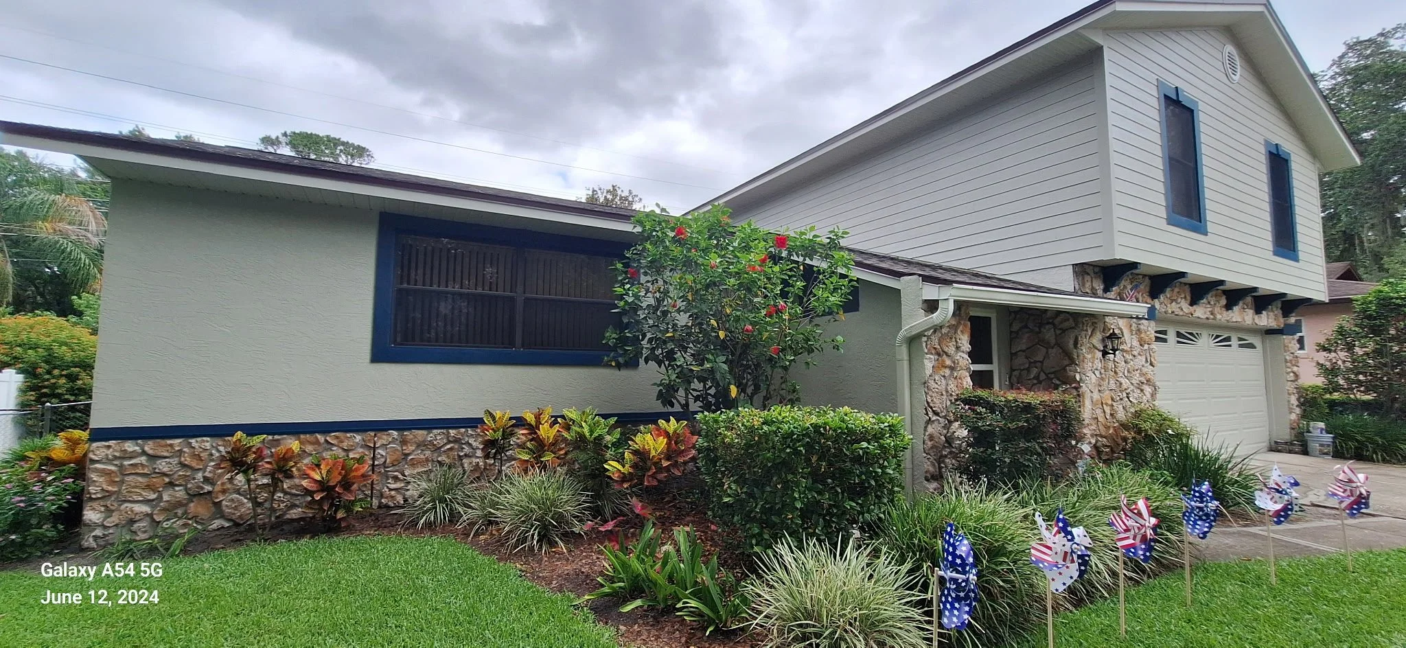 Orlando Florida exterior house painting project featuring modern neutral stucco with navy blue trim and stone accents by Coats of Quality Painting