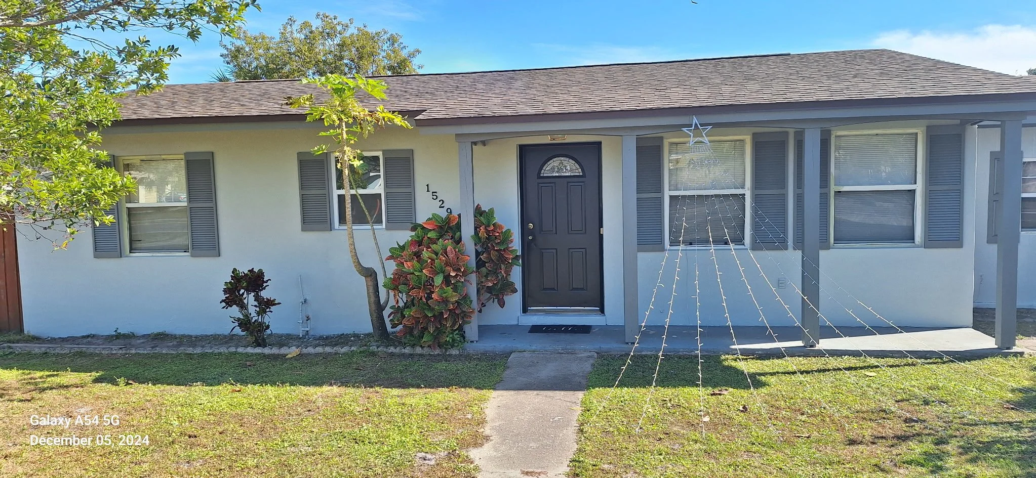 Exterior house painting in Ormond Beach, Florida — freshly painted light gray home with charcoal shutters and front door by Coats of Quality Painting, trusted local Volusia County painters