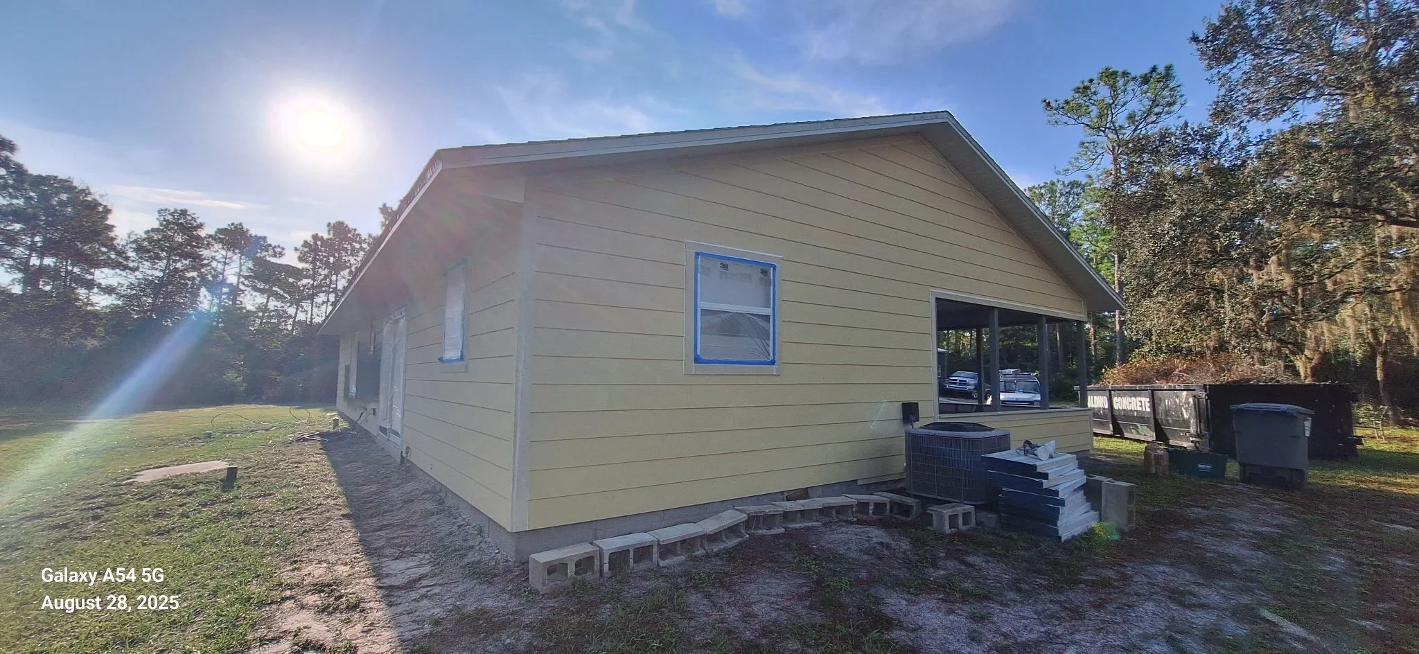 Rear elevation of a New Smyrna Beach home during exterior painting, showing partially completed color application on Hardie board siding. This phase is crucial for ensuring even coverage and durability in Florida’s humid climate.