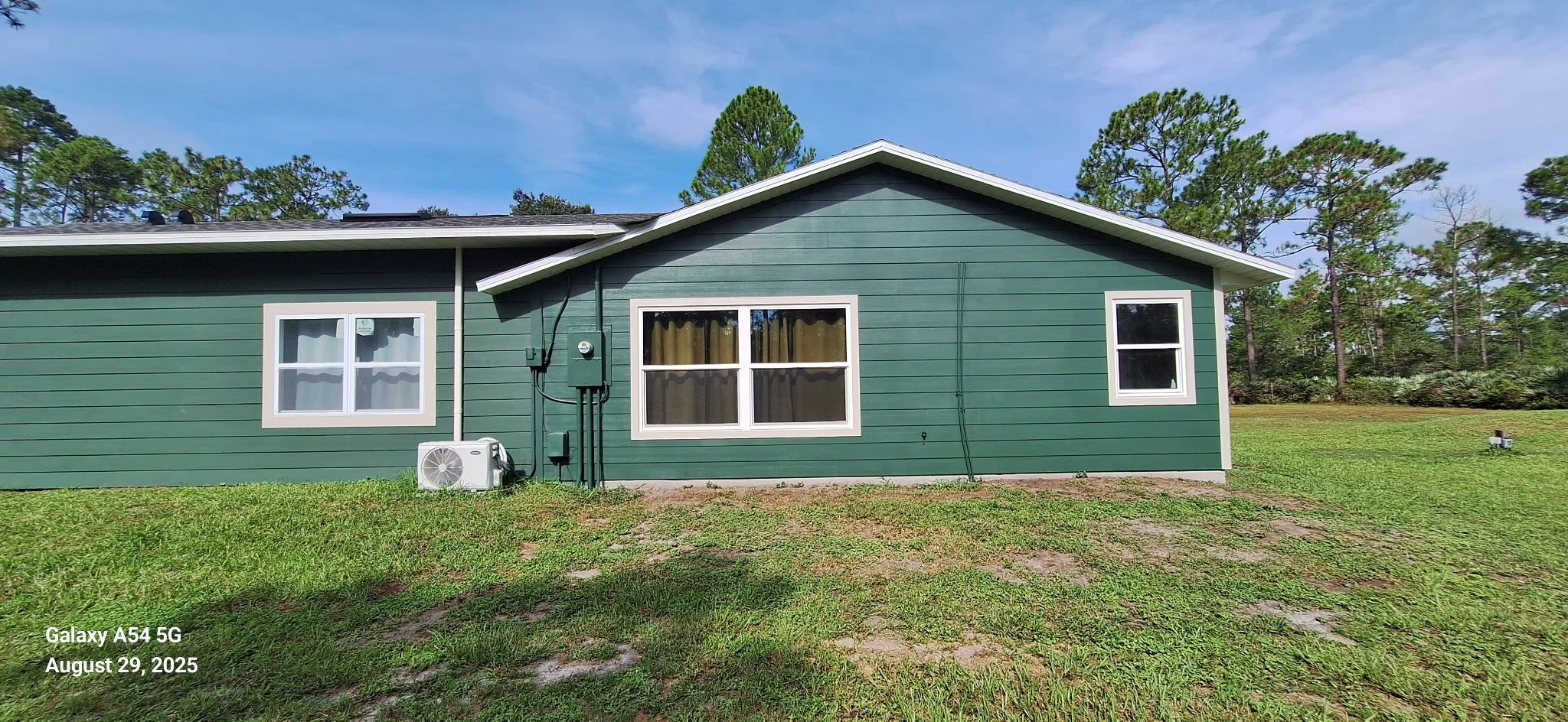 Side view of the finished exterior painting project featuring green Hardie board siding. This modern color choice blends beautifully with the natural surroundings of New Smyrna Beach while standing up to Florida’s sun and humidity.