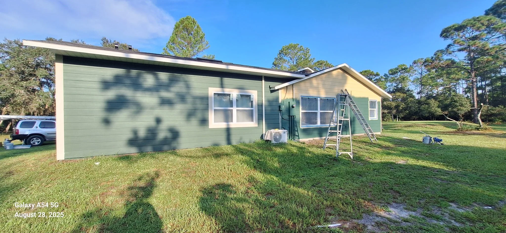 Midway through the exterior painting process, this image shows the new green color being applied to Hardie board siding. The paint system was selected for durability, UV resistance, and moisture protection in coastal Florida conditions.