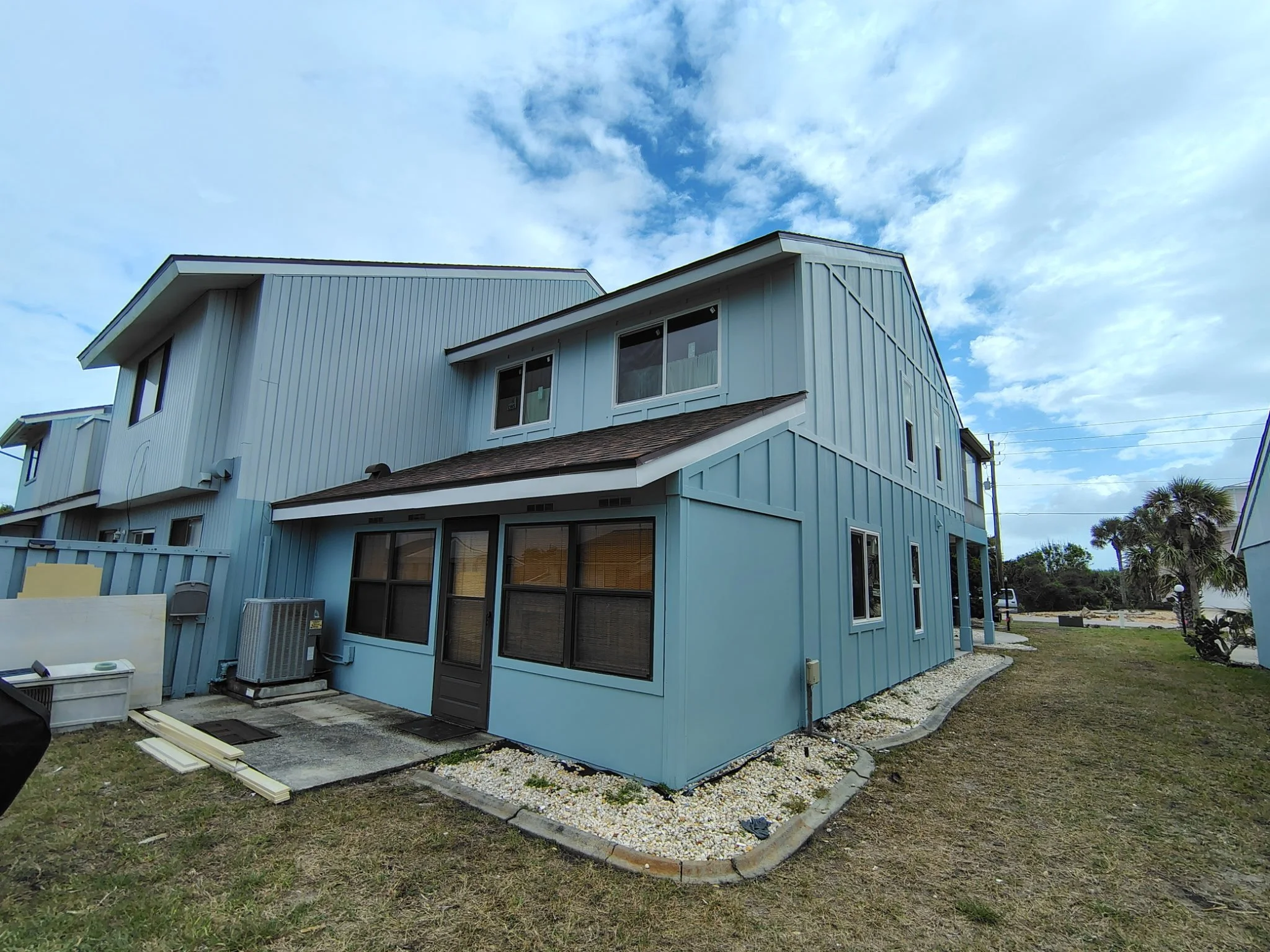 Completed exterior house painting in Flagler Beach FL showing rear angle of coastal blue Hardie board home with fresh trim and clean lines