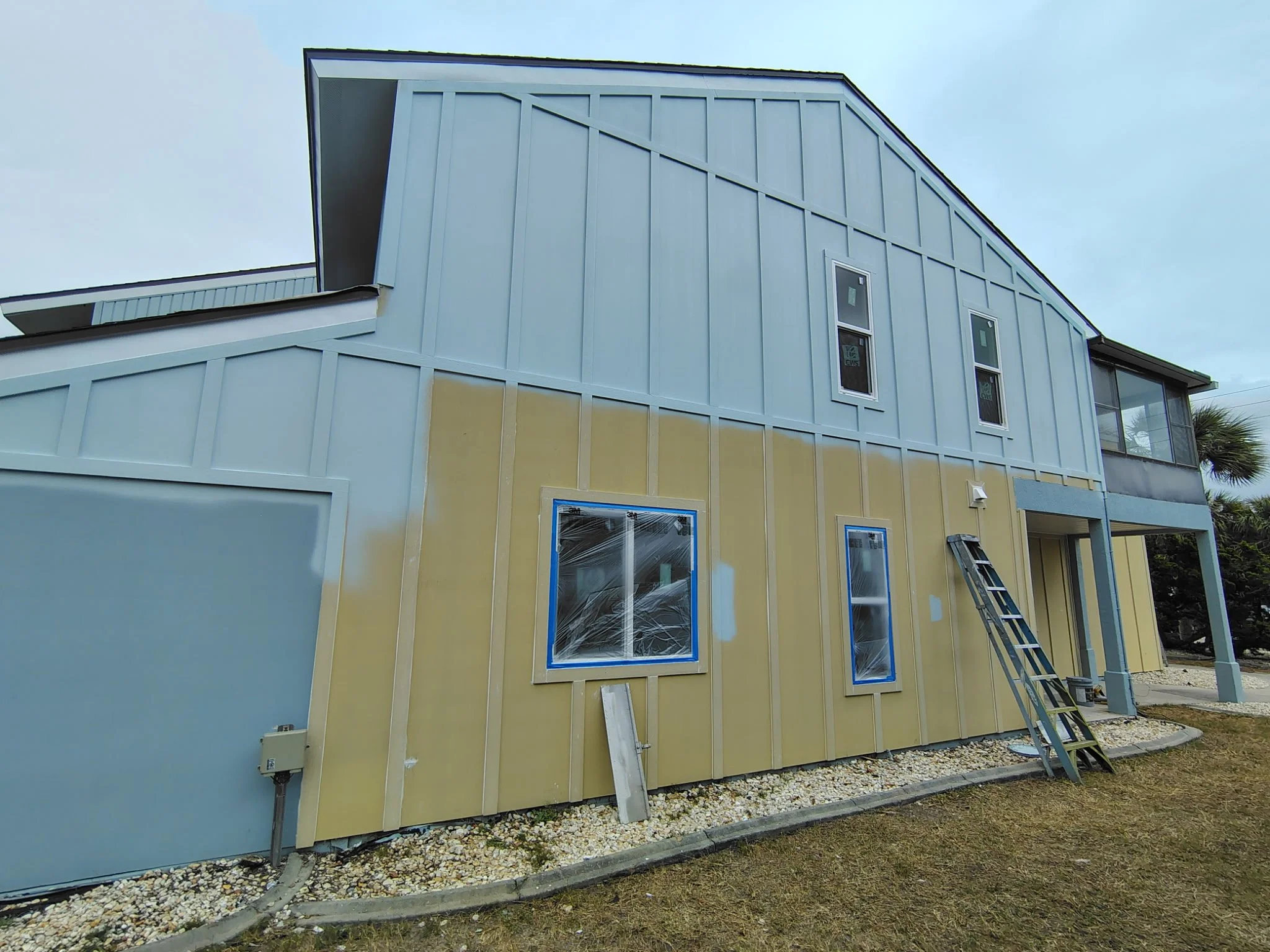 Large exterior wall showing before and during painting with blue siding in South Daytona Florida