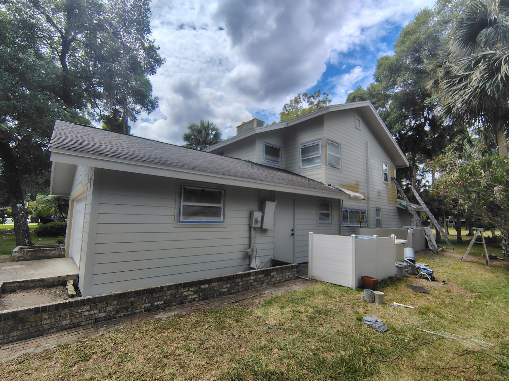 Exterior painting project in Port Orange Florida showing detailed prep work including masked windows, siding preparation, and surface readiness for final paint application