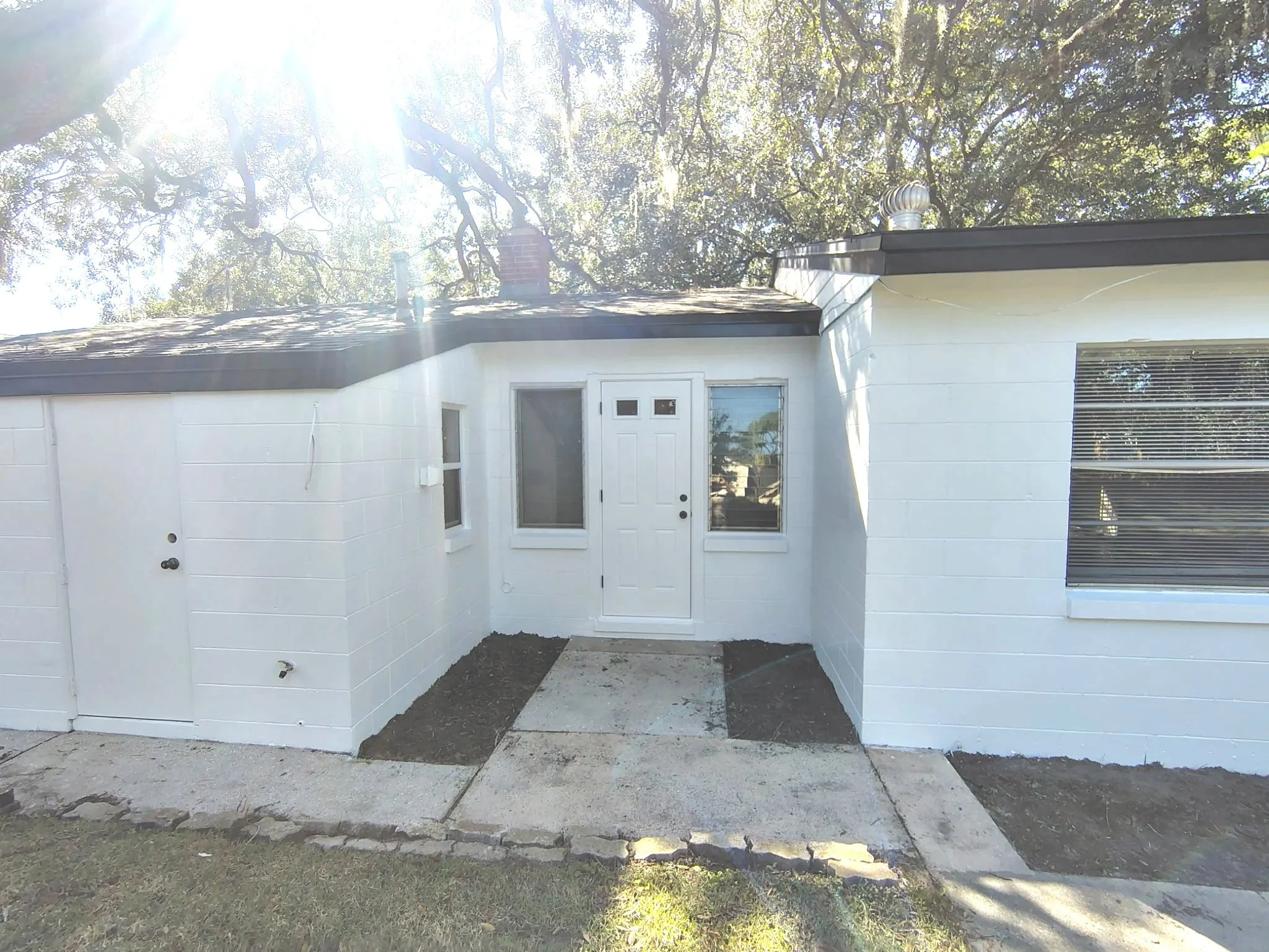 White-painted rear entrance with surrounding windows and clean concrete block walls at a Winter Park house.