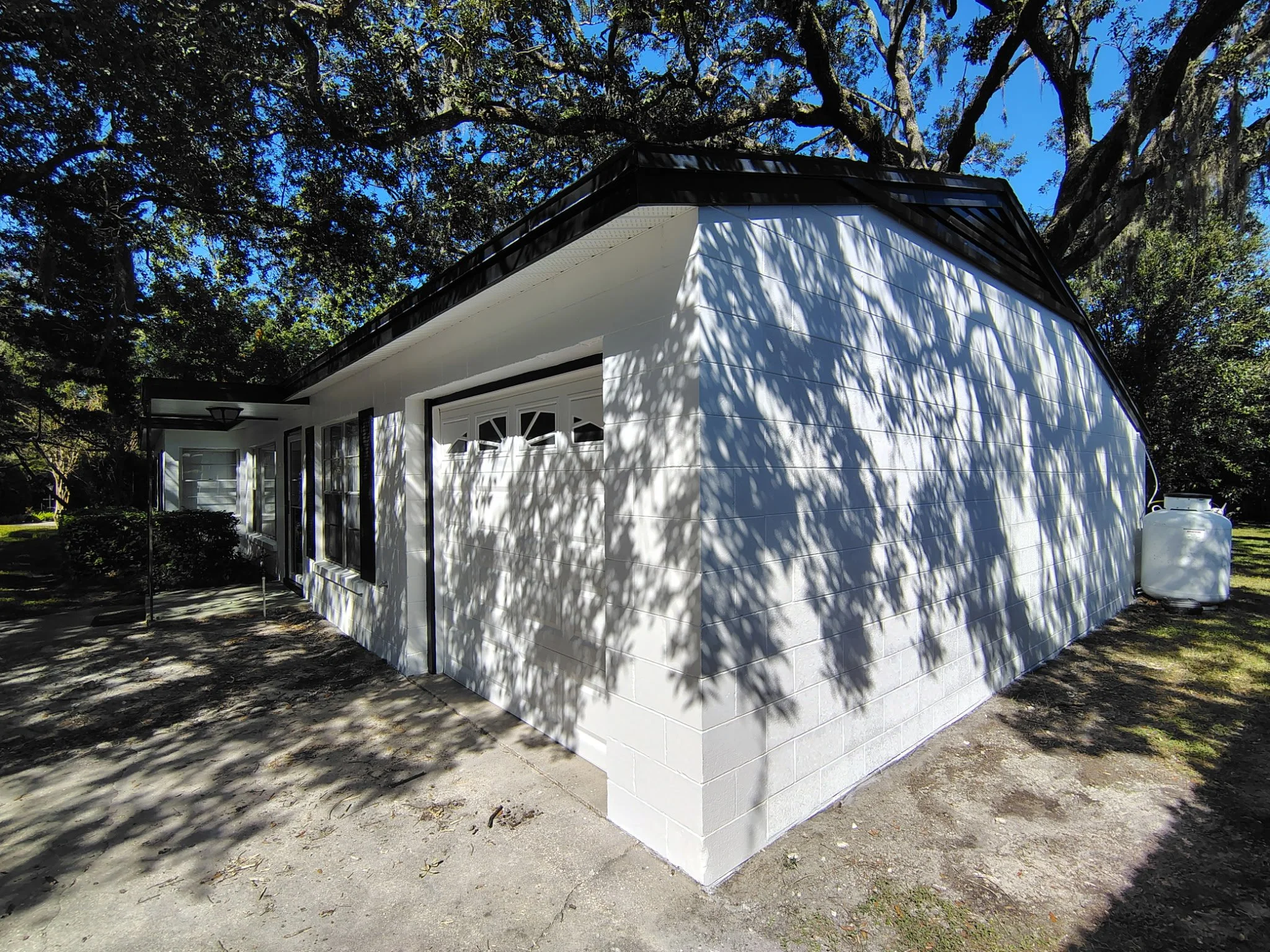 Freshly painted white concrete block home with black roofline accents and garage in Winter Park, Florida.