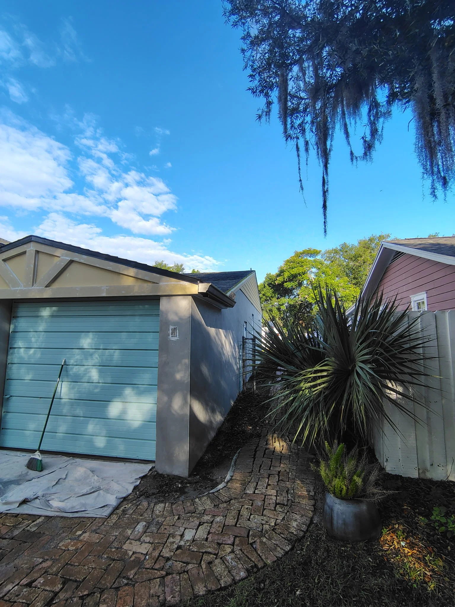 This image captures the garage and side walkway area of a Winter Park exterior painting project. Coats of Quality Painting is preparing the stucco, trim, and garage area for a clean Sherwin-Williams exterior paint finish designed for Central Florida 