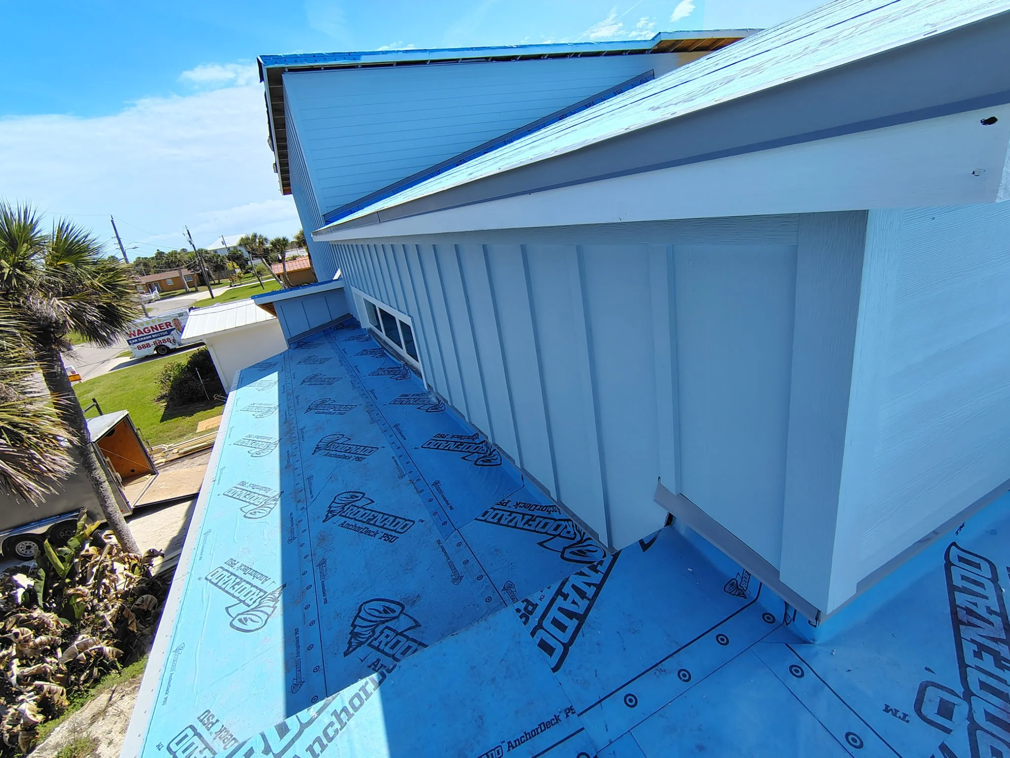 Exterior painting progress view of roofline and siding on South Daytona home with coastal surroundings