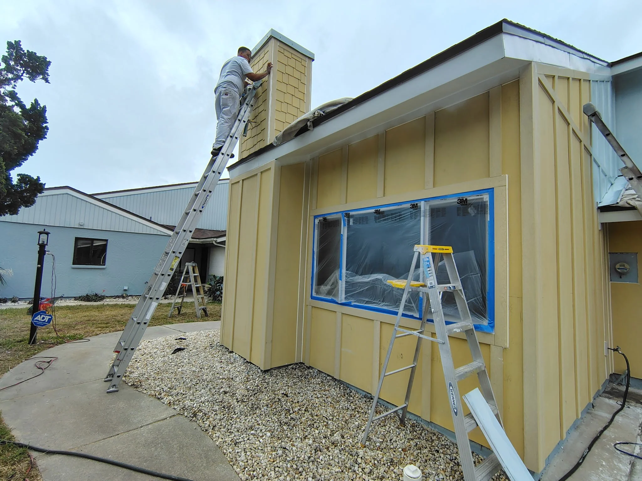 Close-up of chimney painting work on ladder during South Daytona exterior painting project