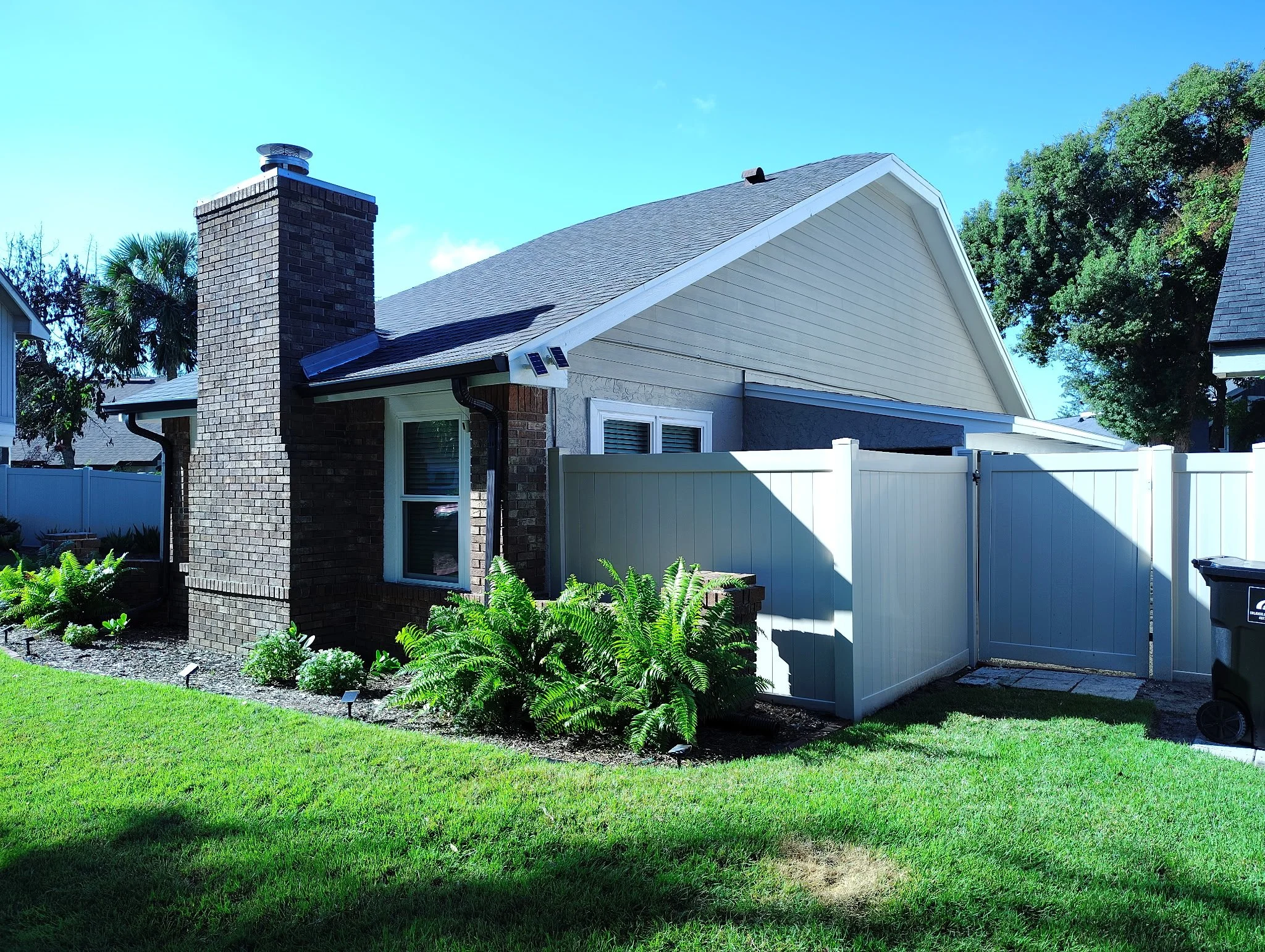 Finished front entrance of an Orlando home with neutral textured stucco, dark entry door, white trim, and clean white soffit.