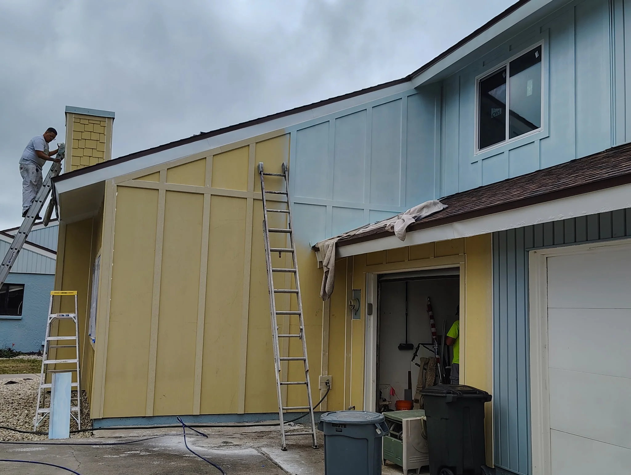 Exterior house painting in progress in South Daytona showing yellow to blue color transition on coastal home