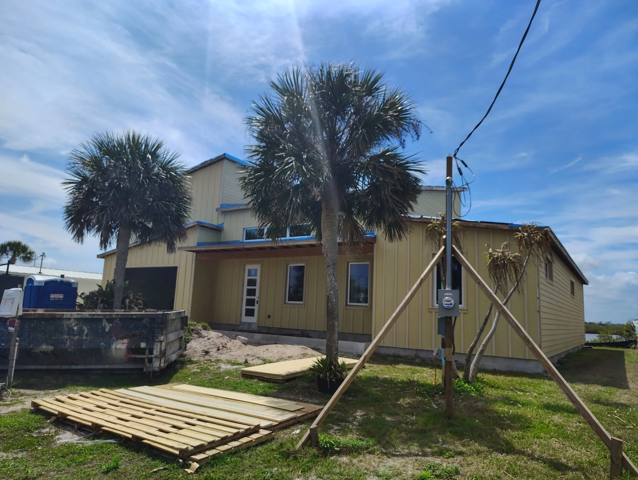 Front view of South Daytona home before exterior painting with palm trees and coastal Florida sky