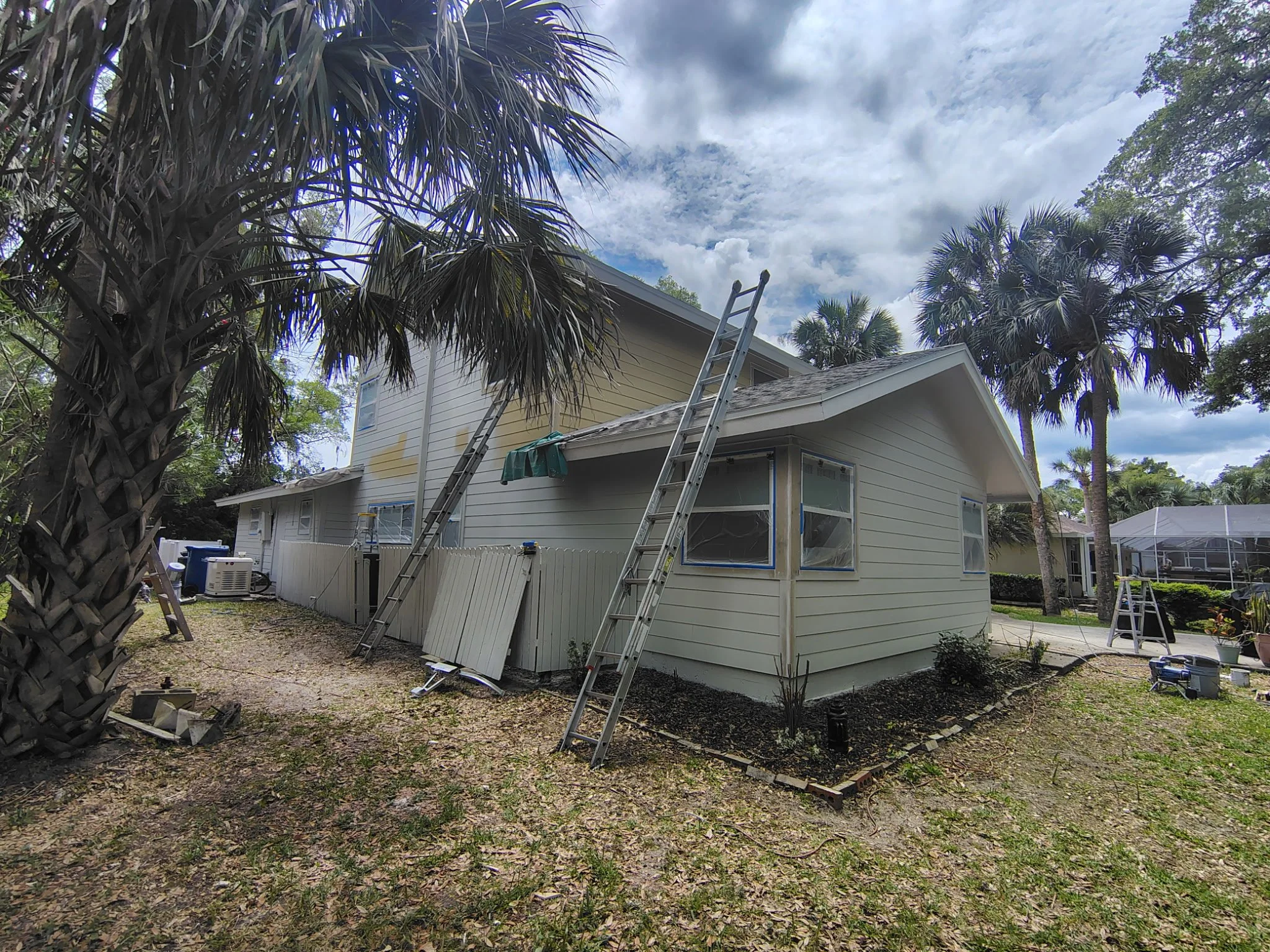 Professional house painters in Port Orange Florida working on exterior surfaces with ladders, masking, and preparation for full repaint
