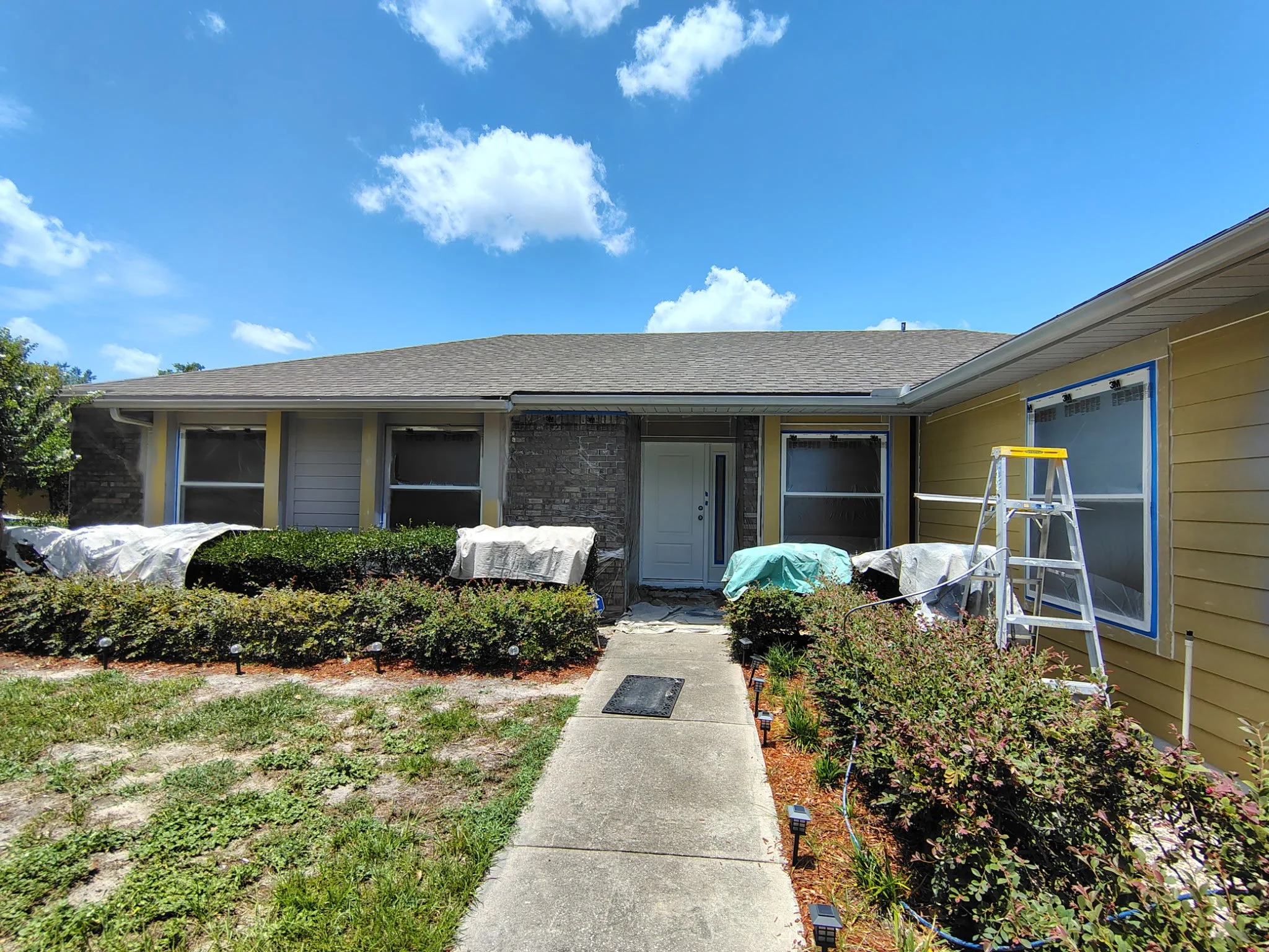 Ocoee FL exterior painting project with front windows, brick and landscaping protected during preparation