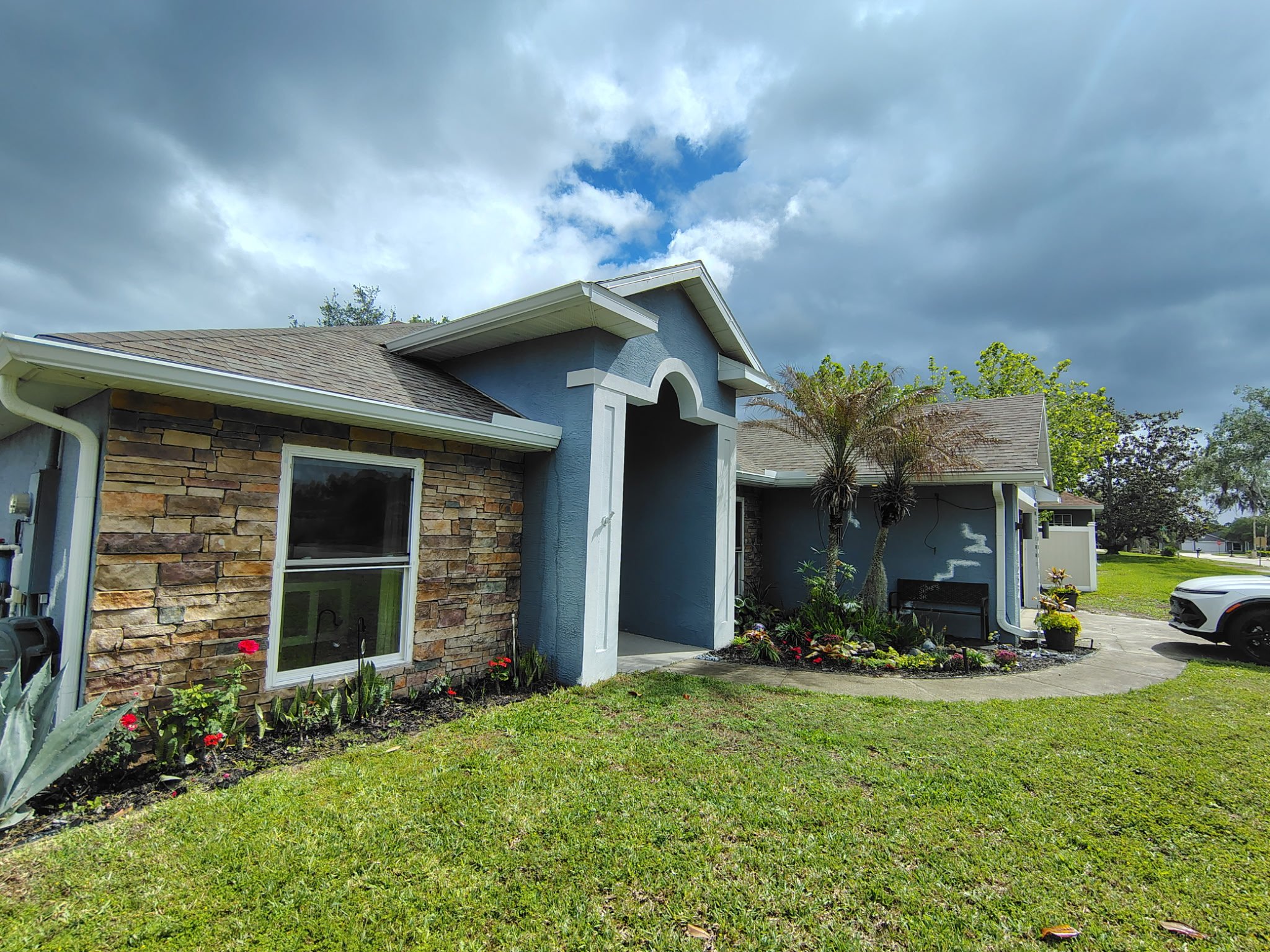 Deltona FL exterior house before painting with blue stucco and stone accent showing fading and wear