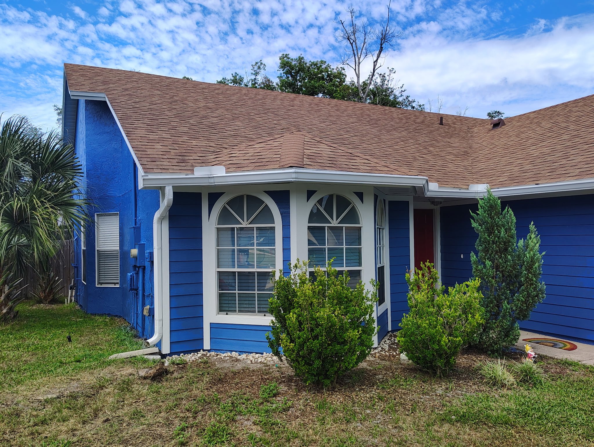 Finished blue Apopka Florida home with white trim around arched front windows after exterior painting.