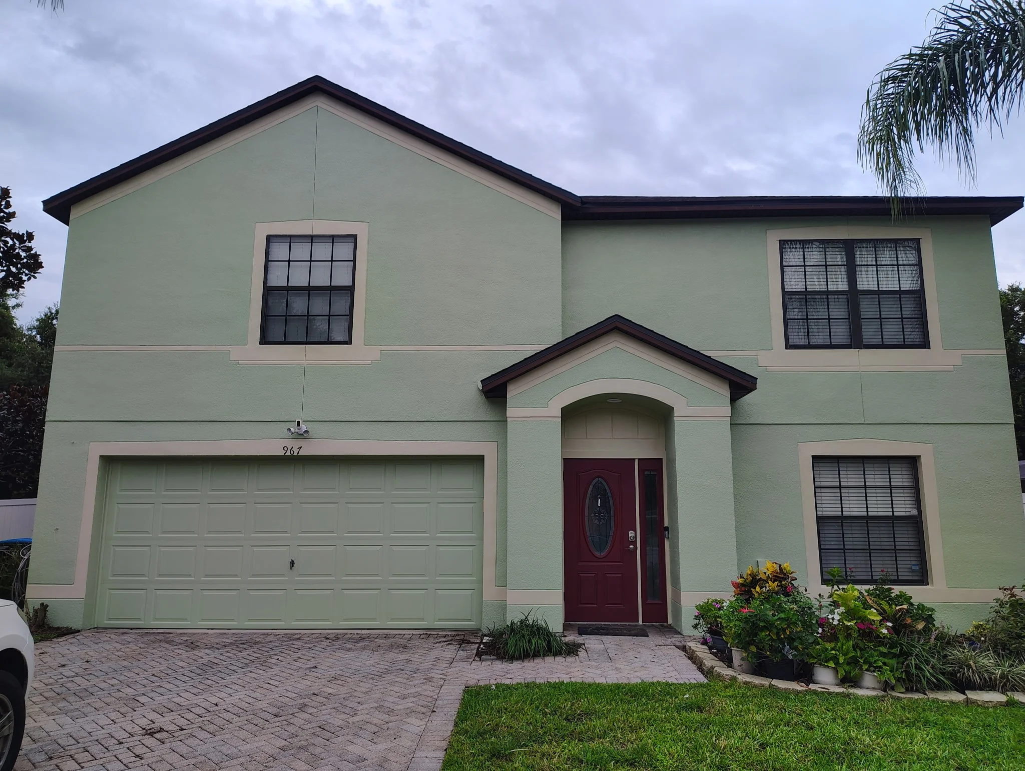 Completed exterior painting on two-story green stucco home in Deltona Florida.
