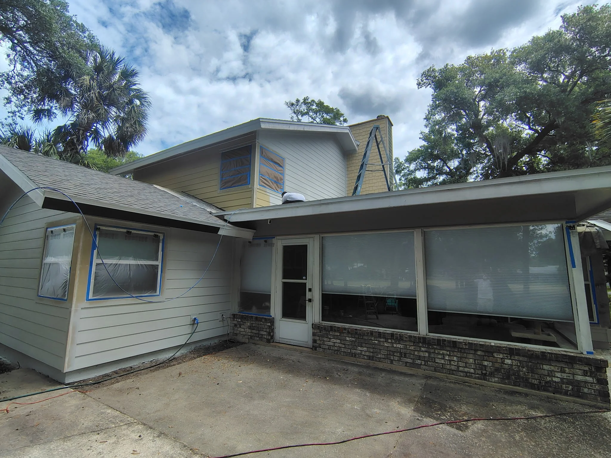 Rear exterior section of Port Orange home showing window masking and surface prep for a complete repaint