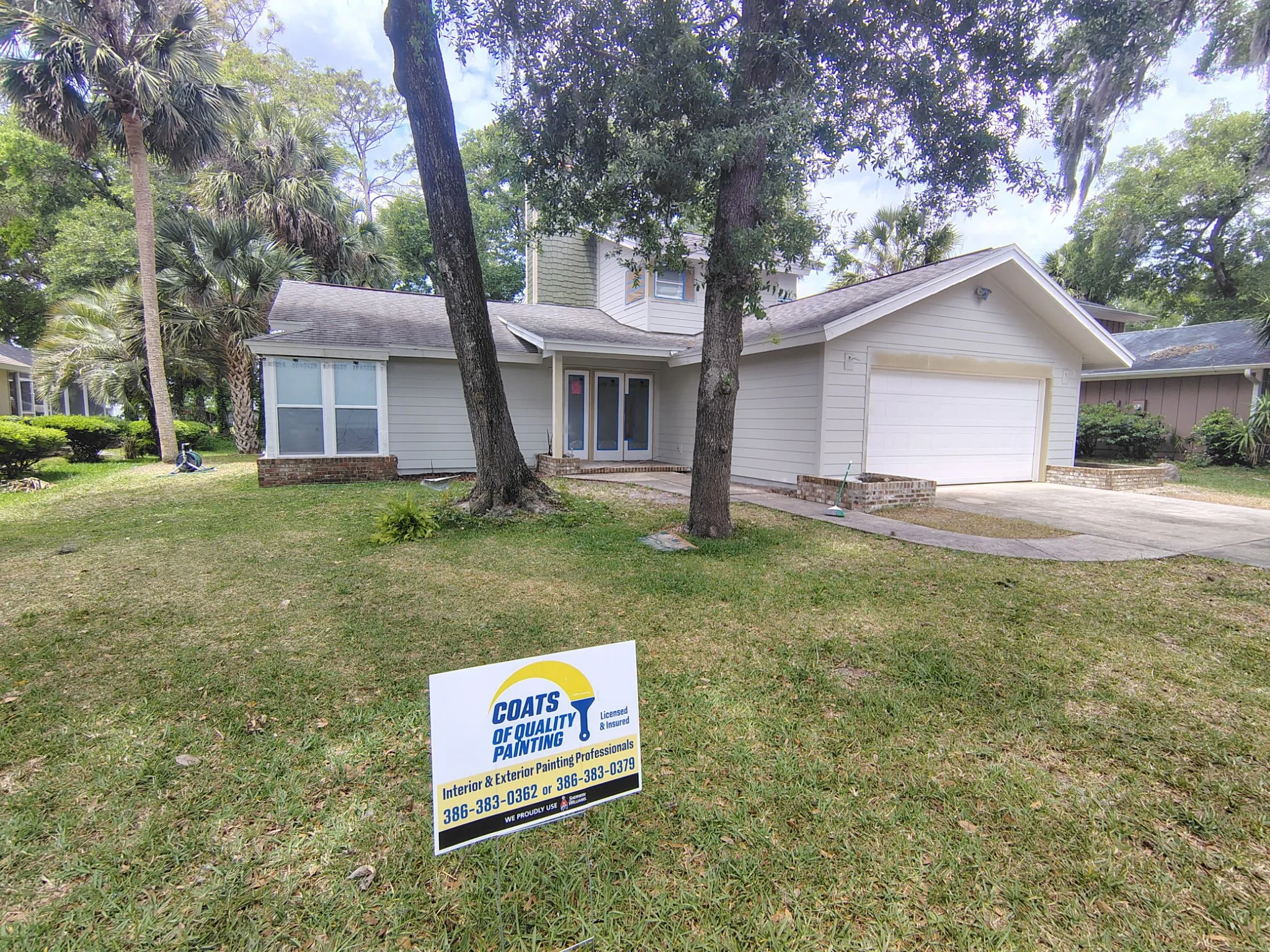 Complete front view of a Port Orange Florida home undergoing exterior repaint with visible preparation and professional painting signage