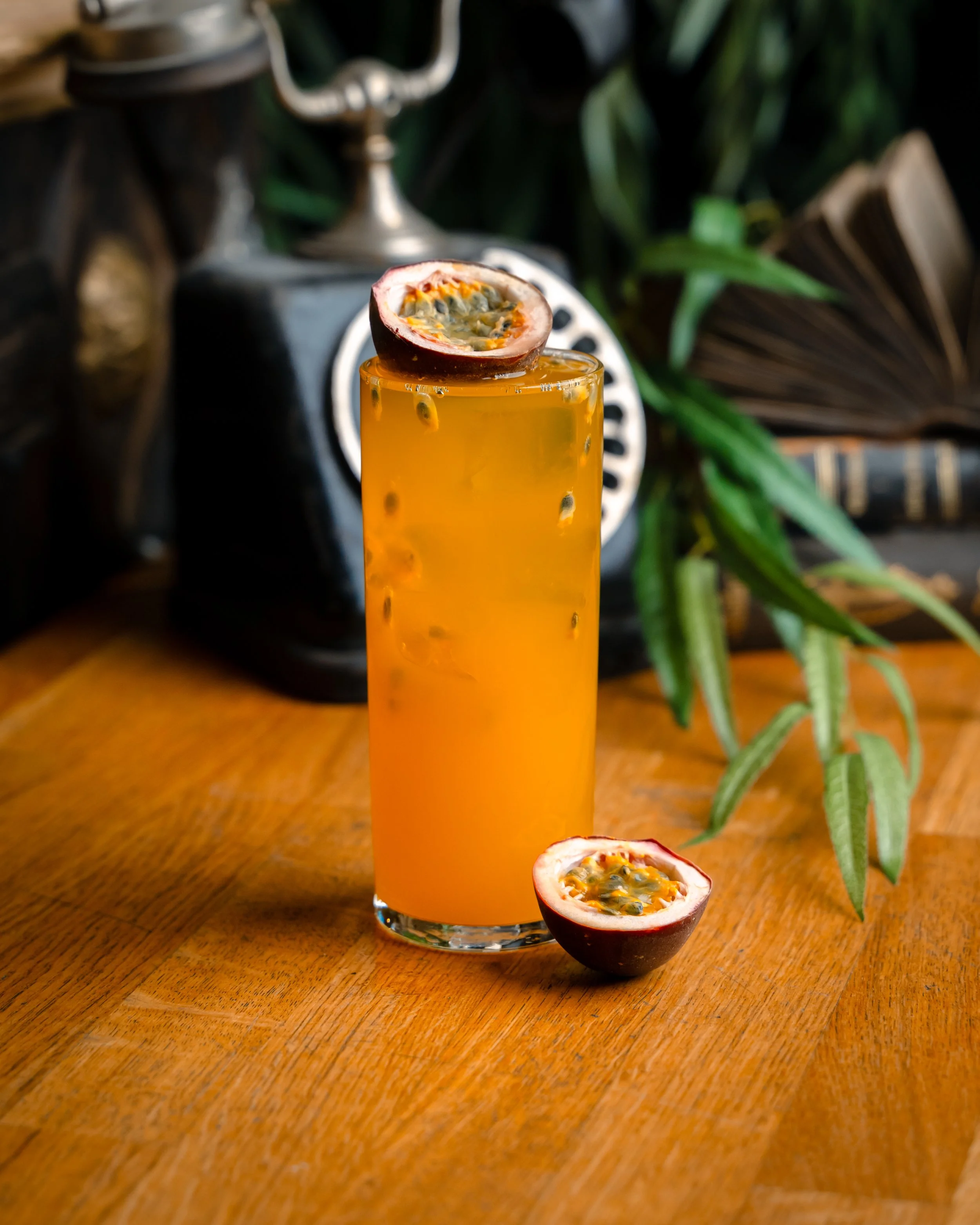 Et høyt glass med passionfrukt cocktail og halvt passionfrukt på siden.
