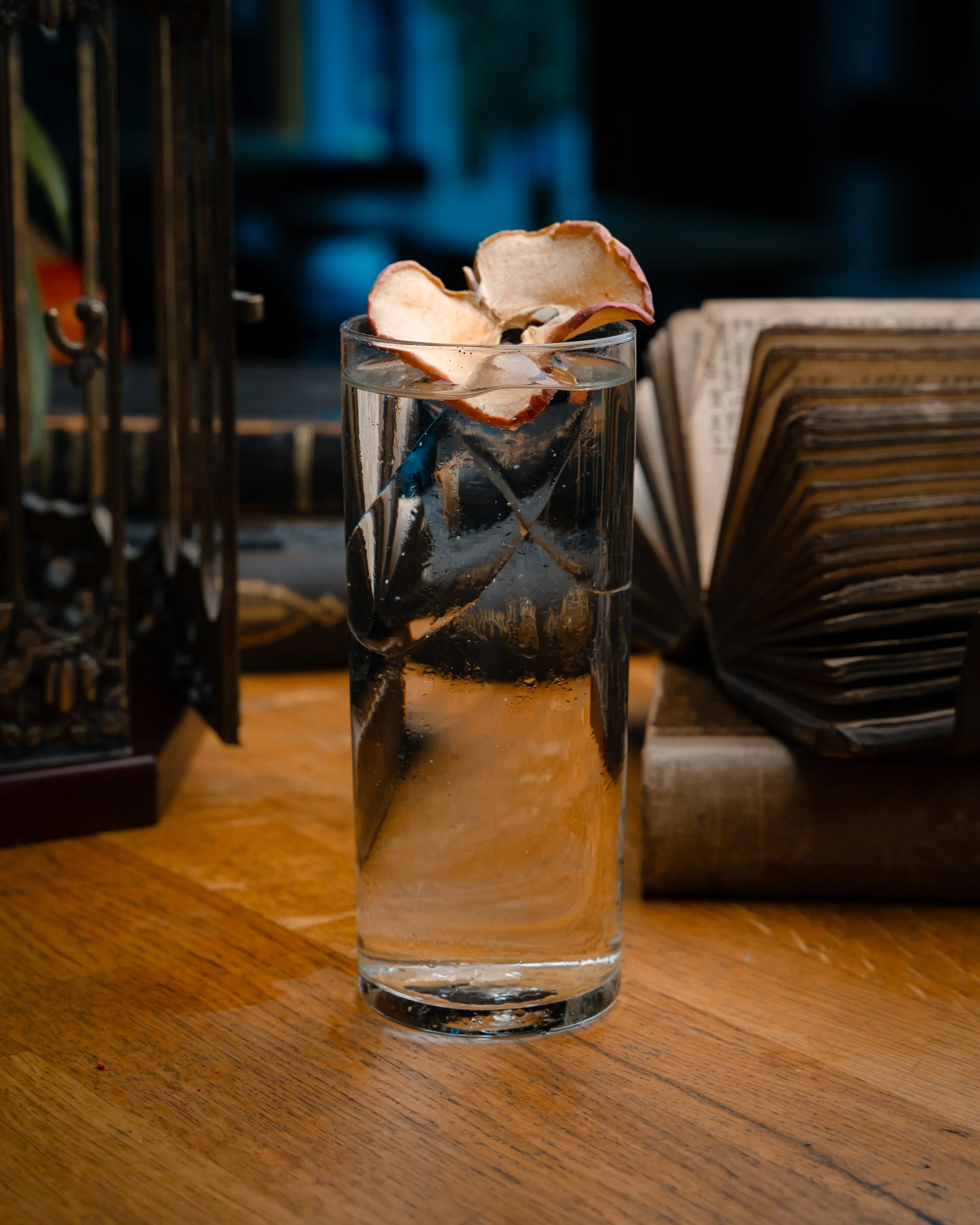 Et høyt glass med vann og iskubber, pyntet med en tørket epleskive