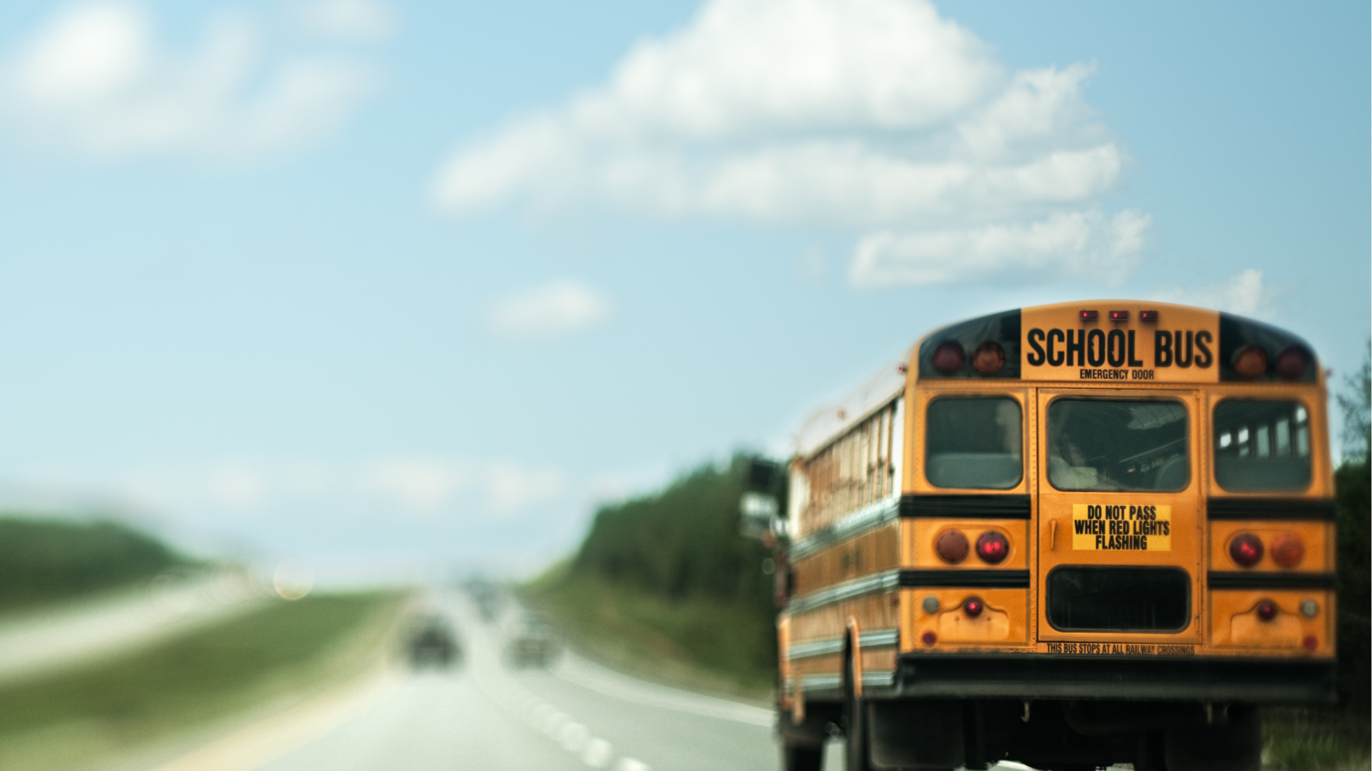 school bus driving down a highway on a beautiful sunny day